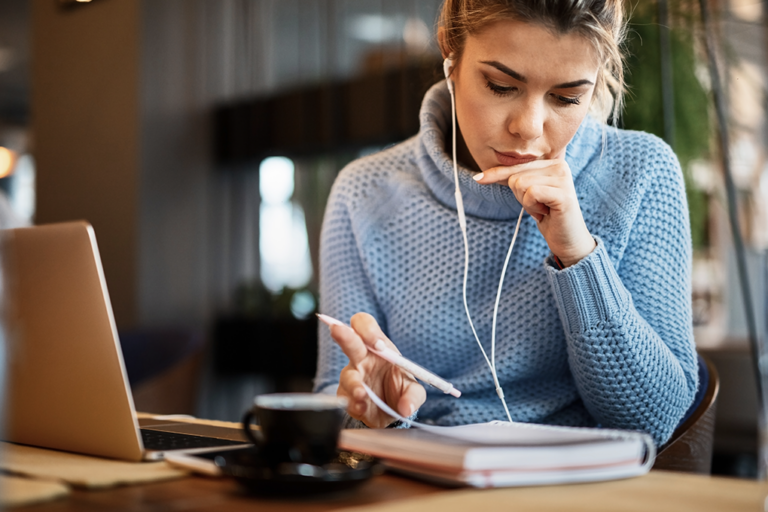 women wearing headphones taking notes on a pad