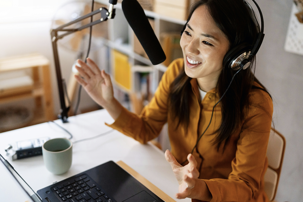 une femme heureuse qui parle dans un microphone relié à son bureau