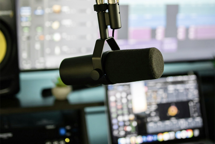 A voice recording microphone in front of a laptop and a pc