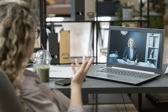 Uma senhora assiste a uma reunião de vídeo no seu computador portátil numa sala de escritório