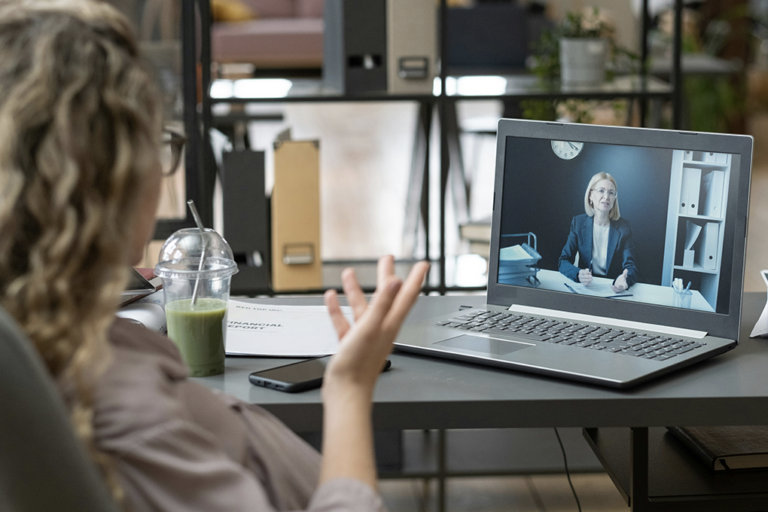 Une femme participe à une réunion vidéo avec son ordinateur portable dans un bureau.