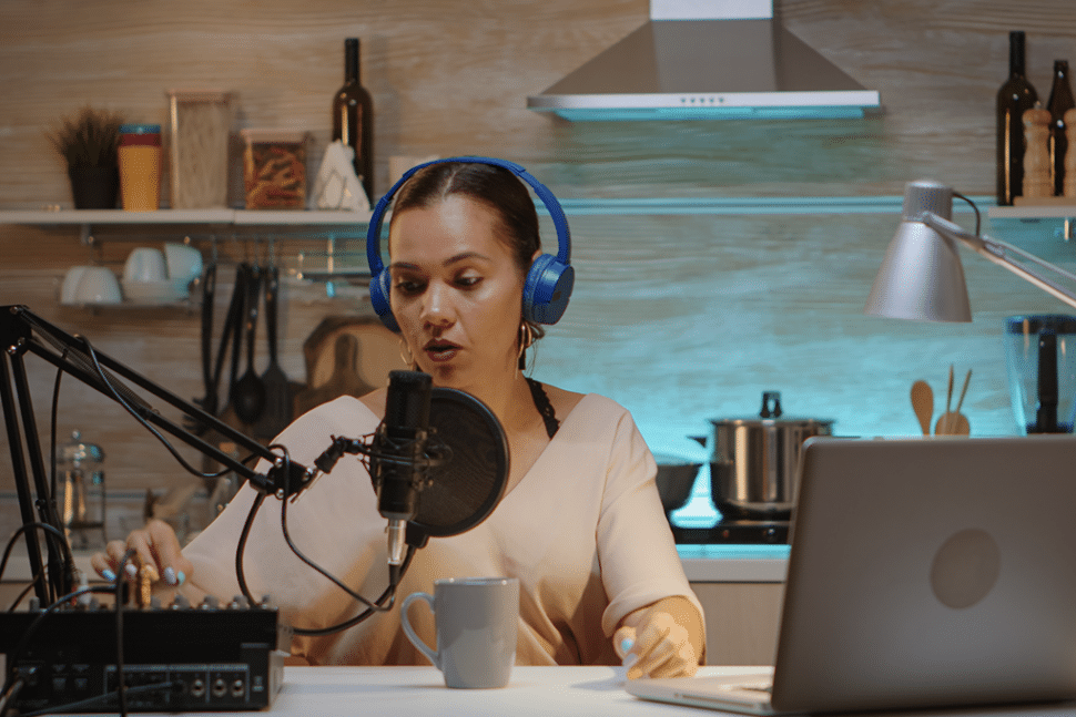 A lady transcribing a job using a microphone, headphones, and a laptop in her room