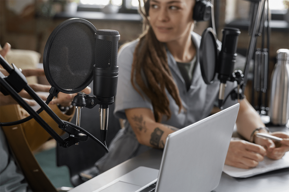 A lady transcribing in an office room using a microphone, headphones, and a laptop