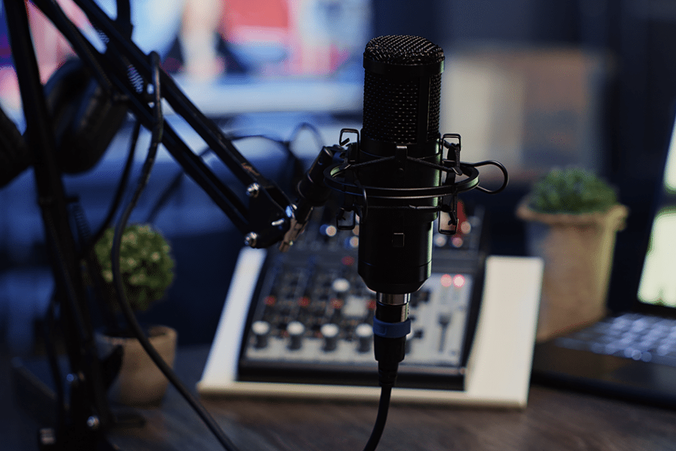 a recording booth, a microphone is standing up with a mixer in the background