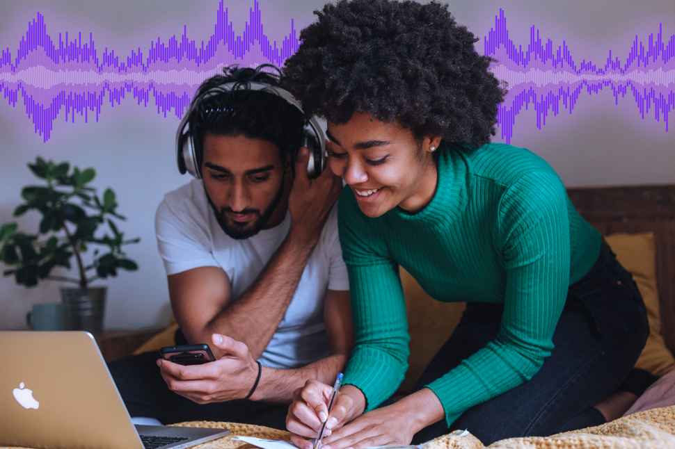 arka planda ses dalgaları olan bir dizüstü bilgisayarın önünde duran bir kadın ve bir erkek