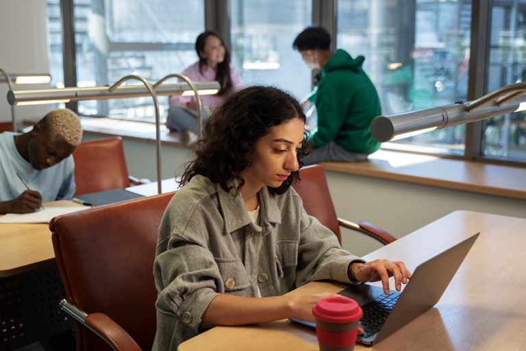 Étudiante transcrivant sur son ordinateur portable dans un café très fréquenté