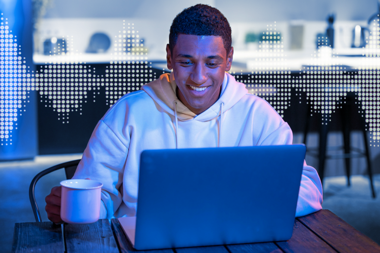 mand kigger på glødende laptopskærm og smiler