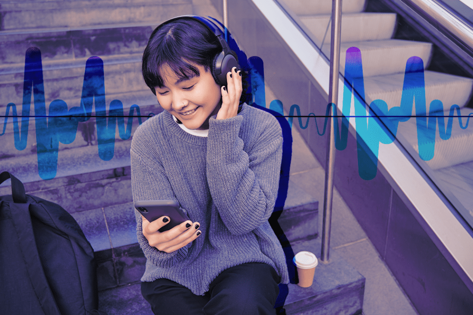 Frau hört etwas über Kopfhörer und schaut auf ihr Telefon