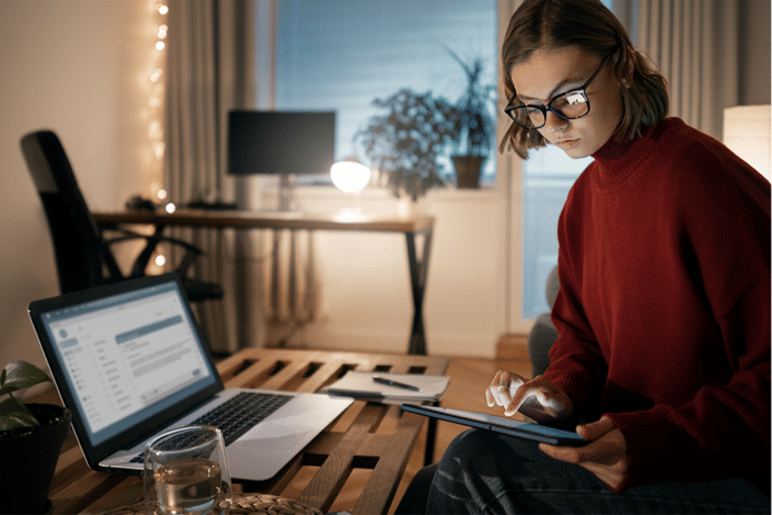 woman checking a tablet with a transcription program open on her laptop